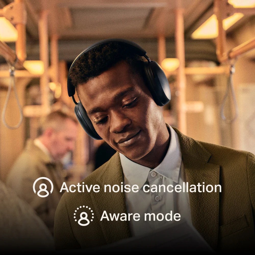 A man wearing Sonos Ace headphones, standing on a subway train. The text 